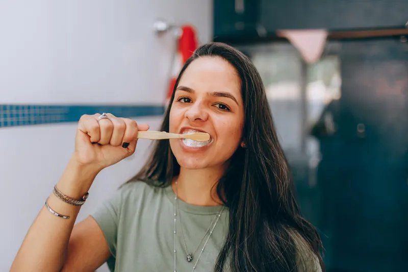 A smiling young woman brushing her teeth