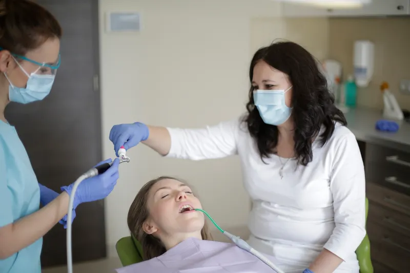 A woman lying back in a dental chair while her teeth are cleaned