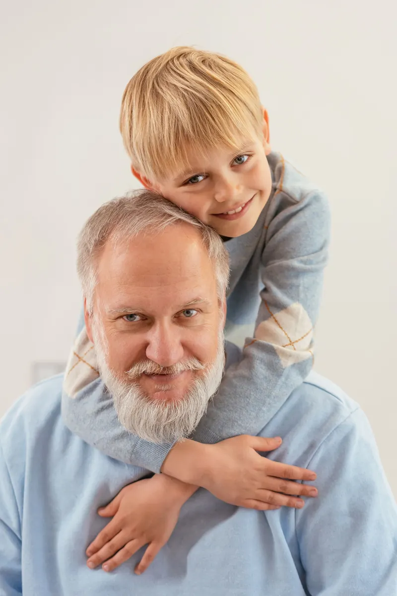 A grandfather and his grandson hugging, both smiling